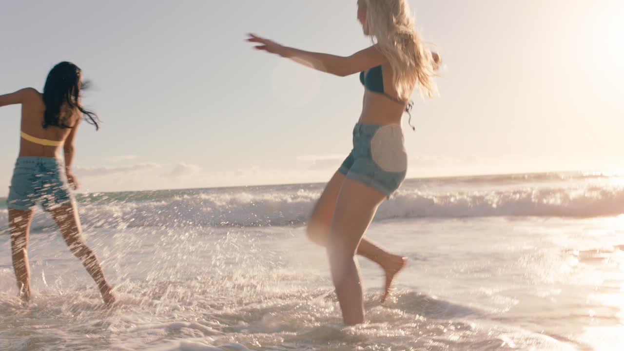 해변에 있는 여자 친구 들 이 서로 바 ⁇ 물 을  ⁇ 아 즐기고 따뜻 한 여름 날 바 ⁇ 가 에서 게임 을 하고 여름 휴가 를 즐기고 있다