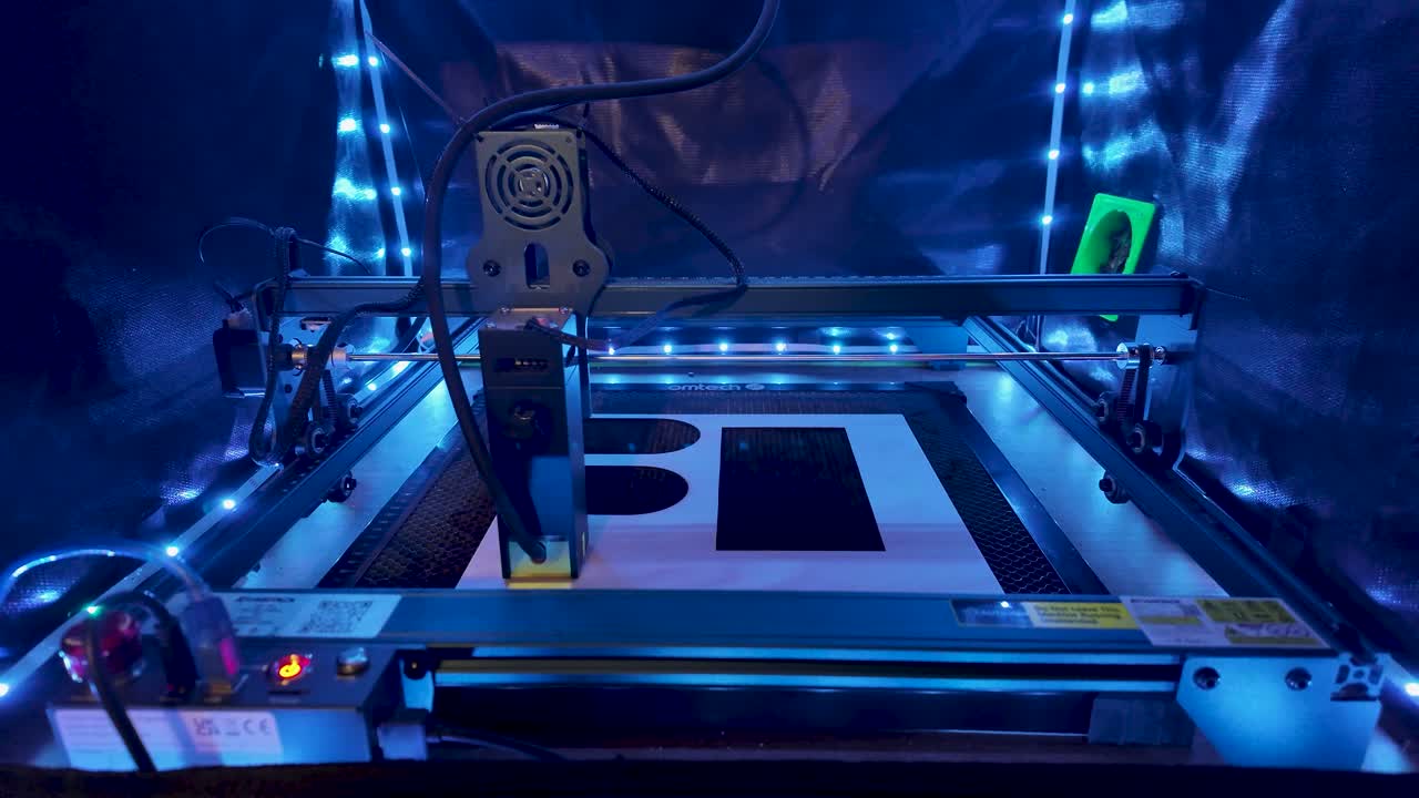 Blue-lit laser engraver in an enclosed workspace, ready for precise engraving projects and production