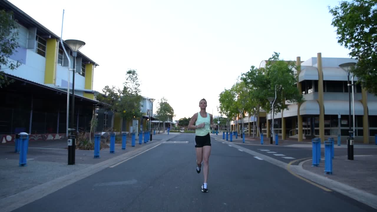 Frontal view of a woman jogging in an empty street.