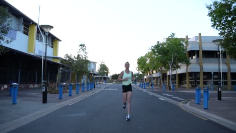 frontal view of a woman jogging in an empty street.