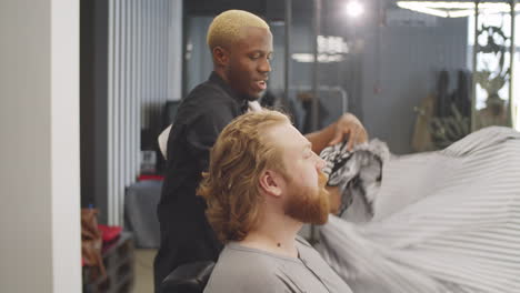 positive barber speaking and shaking hands with male client