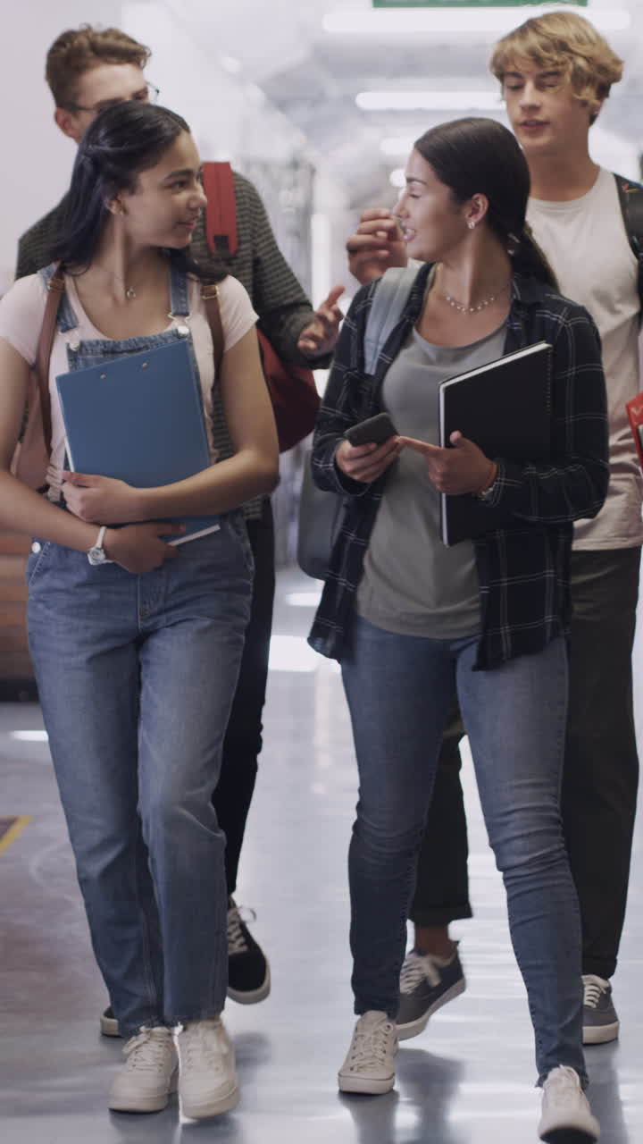 Gruppo di studenti adolescenti che camminano e parlano nel corridoio della scuola