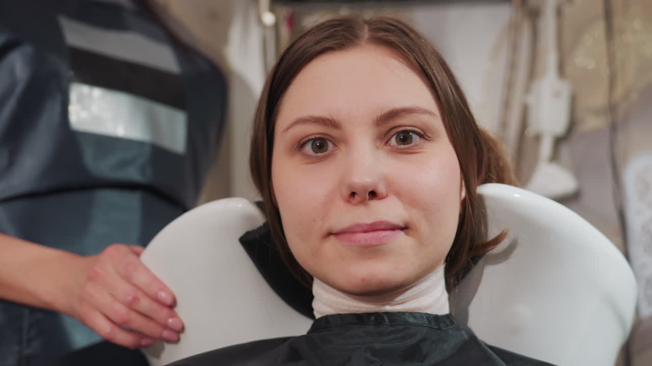 caucasian client relaxing during hair wash with neck cradled in white basin, stylist's hands massaging scalp with warm lather and water droplets, serene salon mood and gentle pampering captured