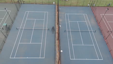 Panorámica-Aérea-Lenta-Sobre-Viejas-Canchas-De-Tenis-Vacías-Con-Diferentes-Colores