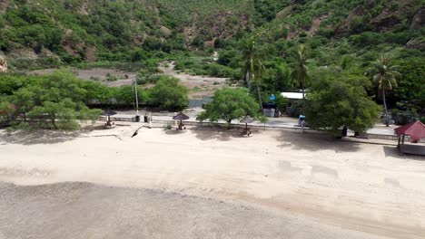 Drone-Aéreo-De-Un-Vehículo-De-Autobús-Azul-Conduciendo-A-Lo-Largo-De-Una-Carretera-Costera-Bordeada-De-árboles-En-La-Isla-Tropical-Timor-Leste,-Sudeste-De-Asia