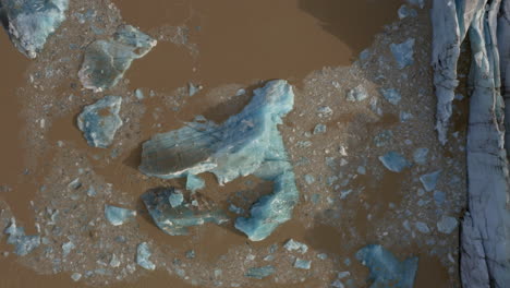 aerial: bird's eye view of collapsing icebergs due to glacier calving on svinafellsjokull glacier in iceland