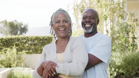 Porträt-Eines-Glücklichen-Afroamerikanischen-Seniorenpaares,-Das-Sich-Im-Sonnigen-Garten-Umarmt,-Zeitlupe