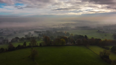 aerial drone hyperlapse on foggy morning with mist moving through valley and sunny rays over fields in calverley village leeds west yorkshire uk