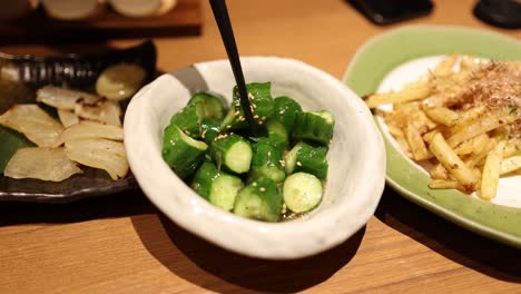 Chopsticks stirring green vegetables in a bowl