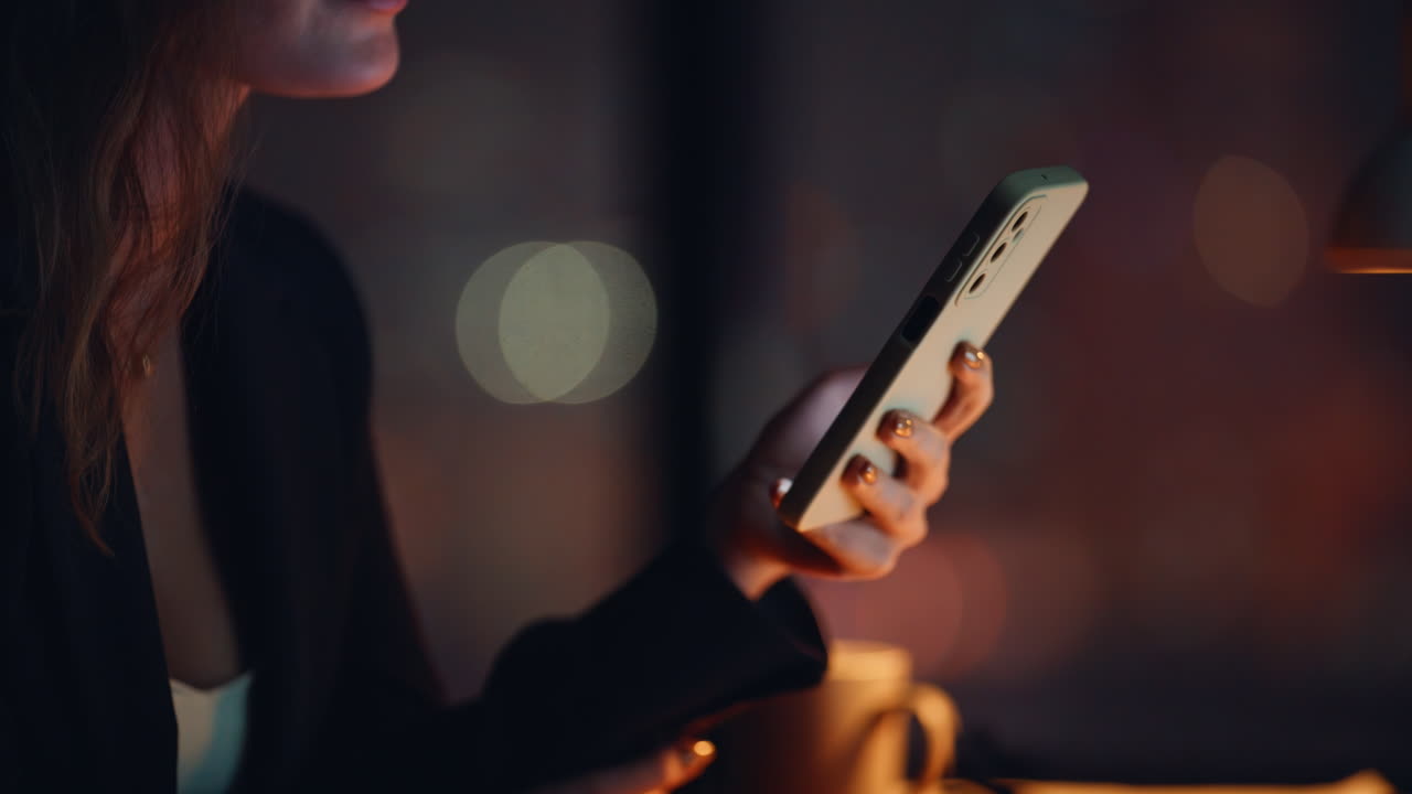 Primo piano serale di un capo sconosciuto che tiene in mano un telefono cellulare. Donna che guarda il cellulare