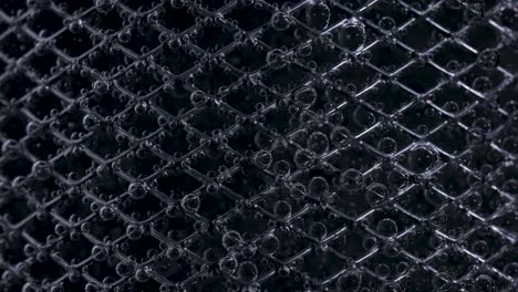 close-up of a dark mesh grid with water droplets