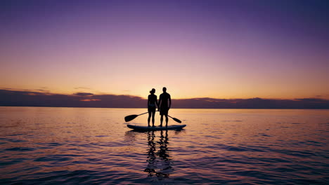 couple paddleboarding at sunset