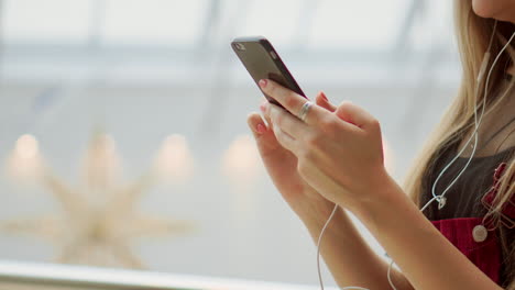 Primer-Plano-De-Niña-Con-Un-Teléfono-Móvil-Escribiendo-Un-Mensaje-De-Texto.-Mire-La-Pantalla-De-Un-Teléfono-Inteligente.-Videoconferencia-A-Través-Del-Teléfono-Móvil-En-El-Aeropuerto.