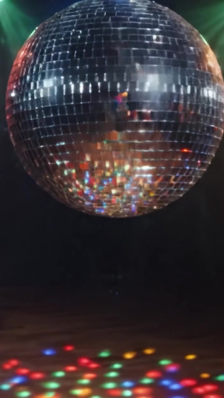 En blændende diskokugle fanger med levende refleksioner i en livlig atmosfære, der oplyser dansegulvet med en eksplosion af farver og energi i en feststemning