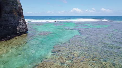 Aerial-wide-shot-showing-clear-water-of-Caribbean-sea-with-coral-reef-underwater-along-rocky-coastline-of-Playa-Fronton,-Las-Galeras-in-Samana