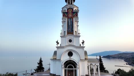 a white church with a tall spire sits on a hill overlooking the black sea in crimea