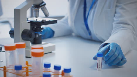 primer plano de un trabajador de laboratorio que realiza investigaciones con un microscopio sosteniendo una muestra de sangre etiquetada como tipo ab
