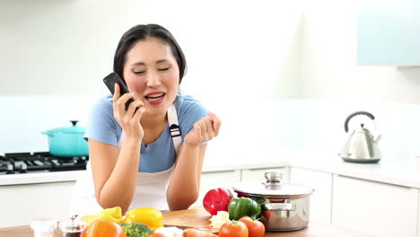 Glückliche-Frau-Bereitet-Das-Abendessen-Vor-Und-Telefoniert