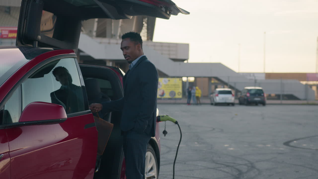 hombre de traje entrando en su coche eléctrico