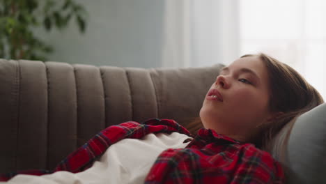 long haired lady in red shirt falls down onto grey couch