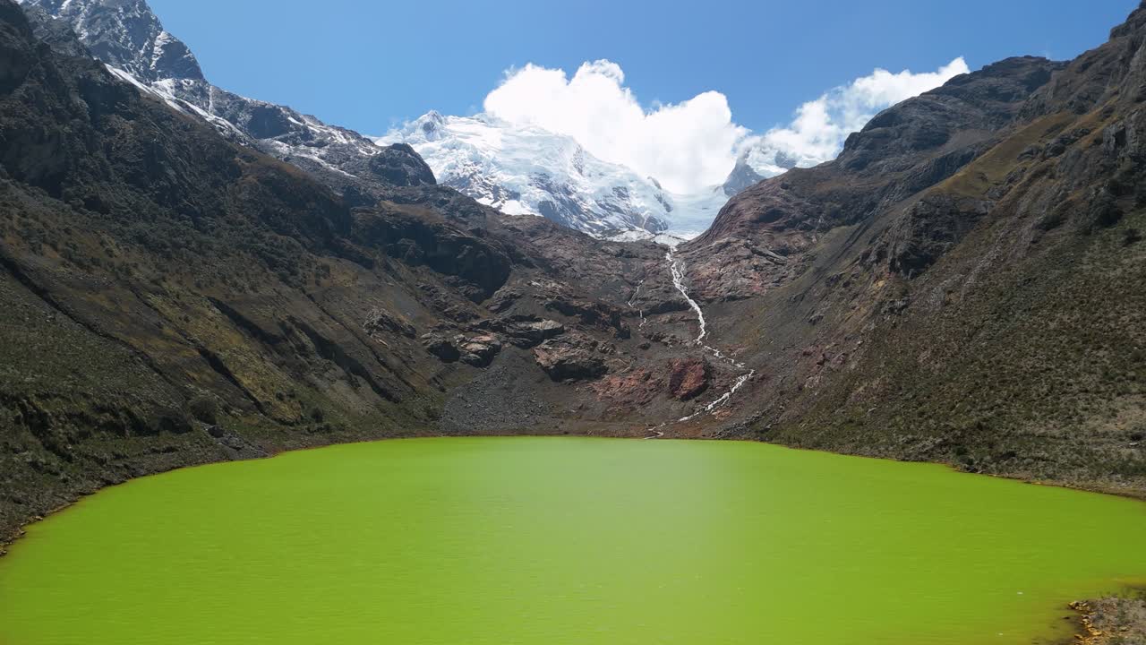 Slow aerial orbit showcases stunning panoramic beauty of Laguna Shallap, capturing its vibrant green water and surrounding majestic, snow-capped peaks of Cordillera Blanca in Peru