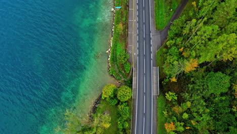 Vista-Aérea-De-Arriba-Hacia-Abajo-De-La-Delgada-Carretera-Cerca-De-La-Orilla-Del-Lago-Attersee-En-Austria