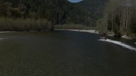 A-jet-boat-moved-up-a-river-with-trees-and-mountains-on-either-side