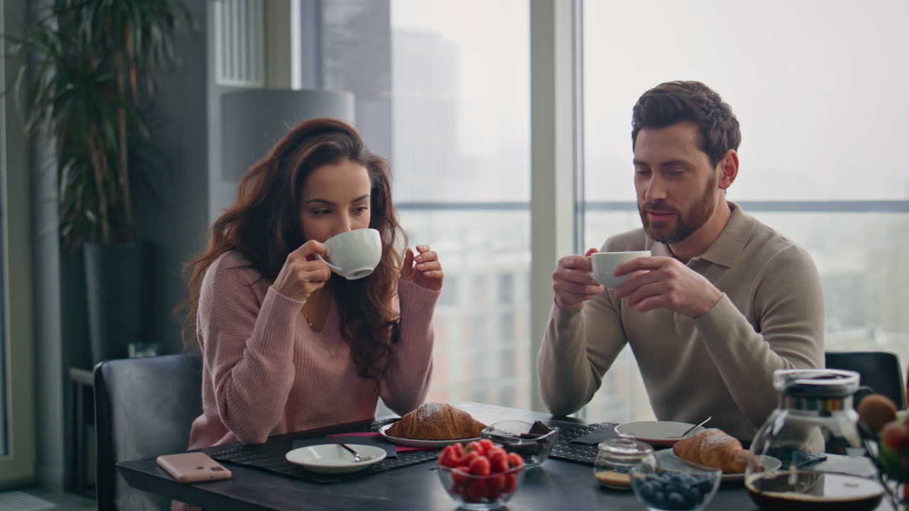 amantes hablando bebiendo café sentados en casa de cerca. pareja disfrutando del desayuno