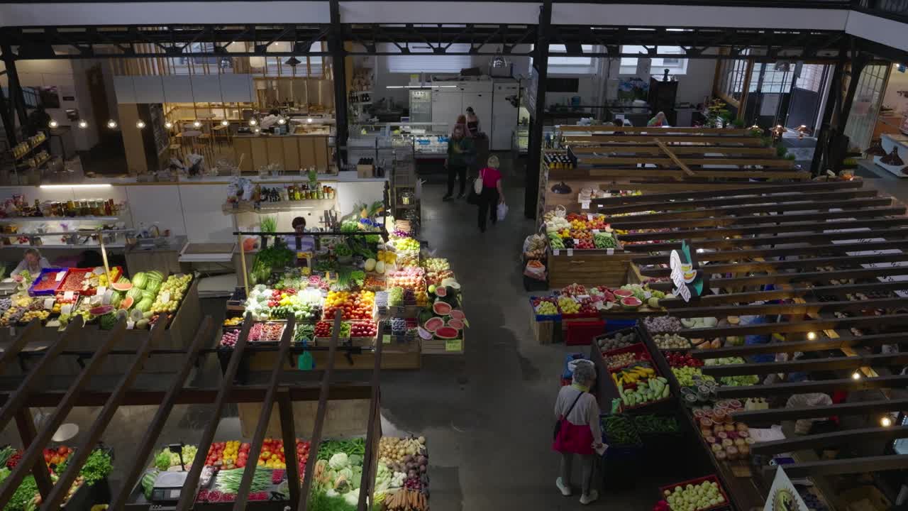 Interior view of Angenskalns Market with people shopping for fruits and vegetables