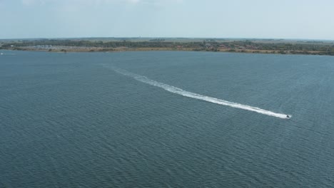 drone - aerial shot a jetski on a blue, wavy and windy sea on a sunny day with white clouds on a island, 25p