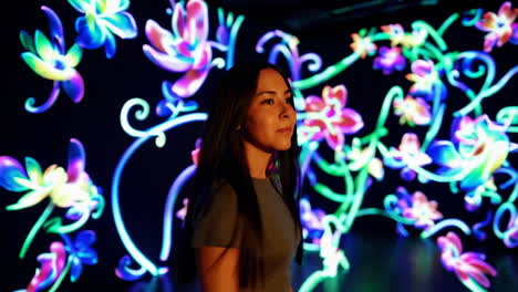 woman enjoying an immersive digital art exhibit with glowing floral patterns