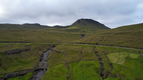 dolly in towards cars driving on faroe islands street during road trip near kvivik