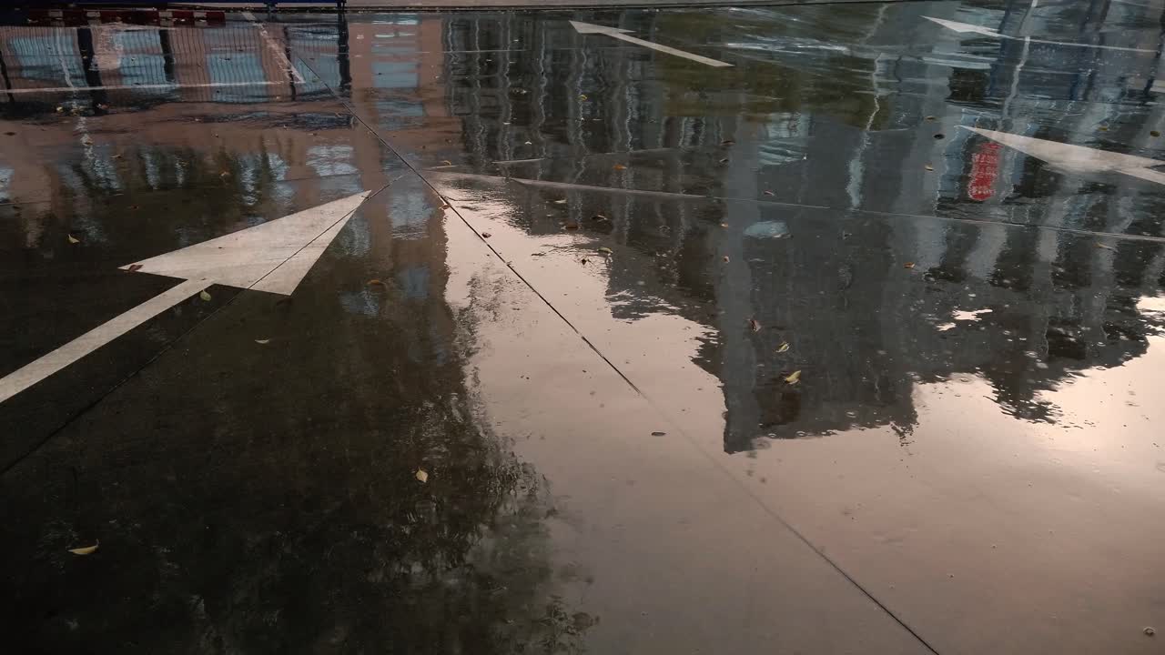 una toma de edificios reflejados en hormigón húmedo cerca de un signo de flecha