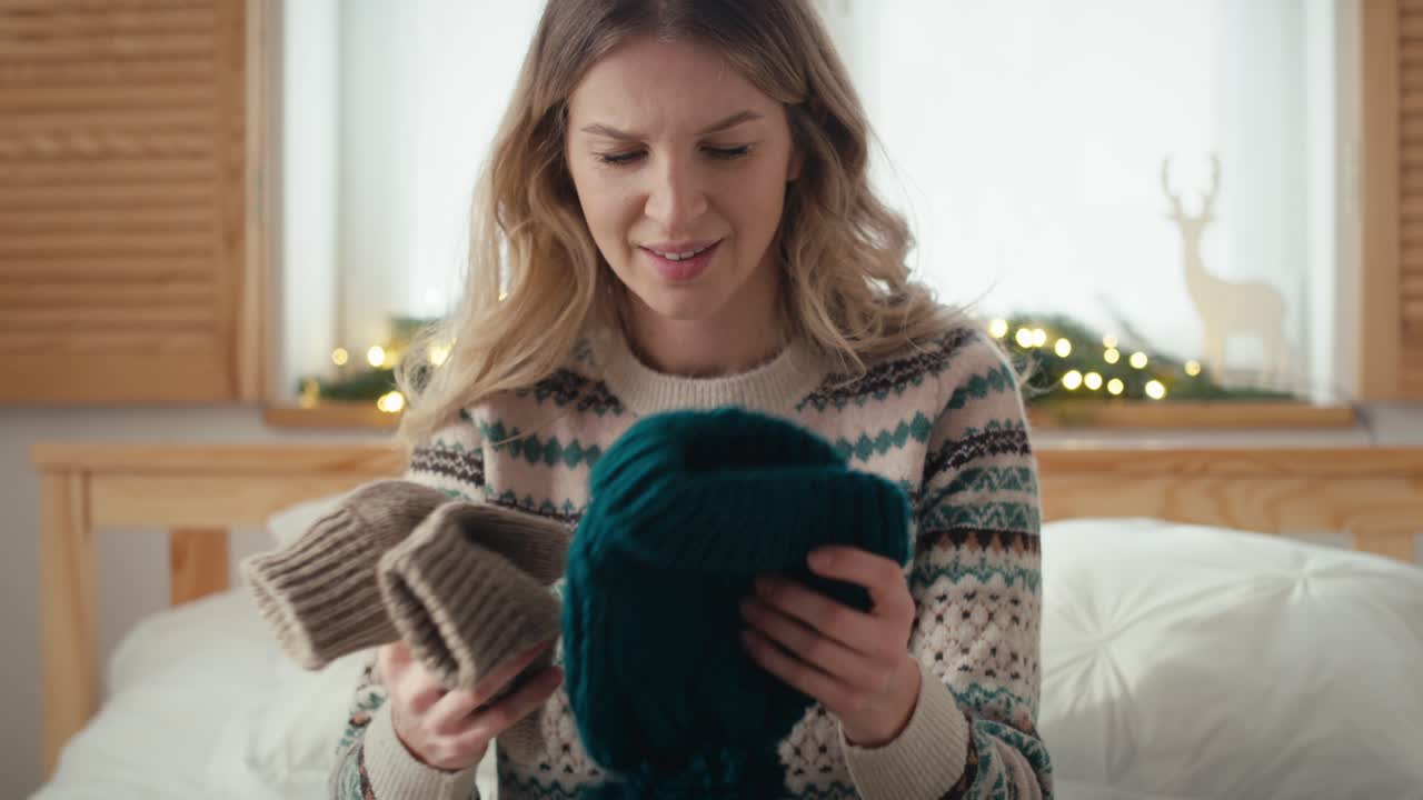 백인 여성이 크리스마스 선물을 열고 실망하고 있습니다.