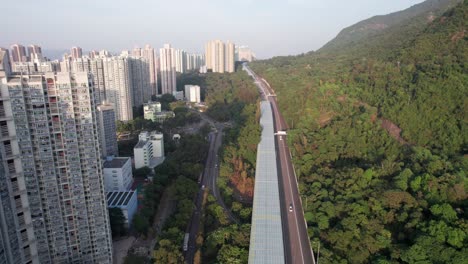 partly covered highway with dense nature on one side and high apartment buildings in ma on shan in hong kong on the other