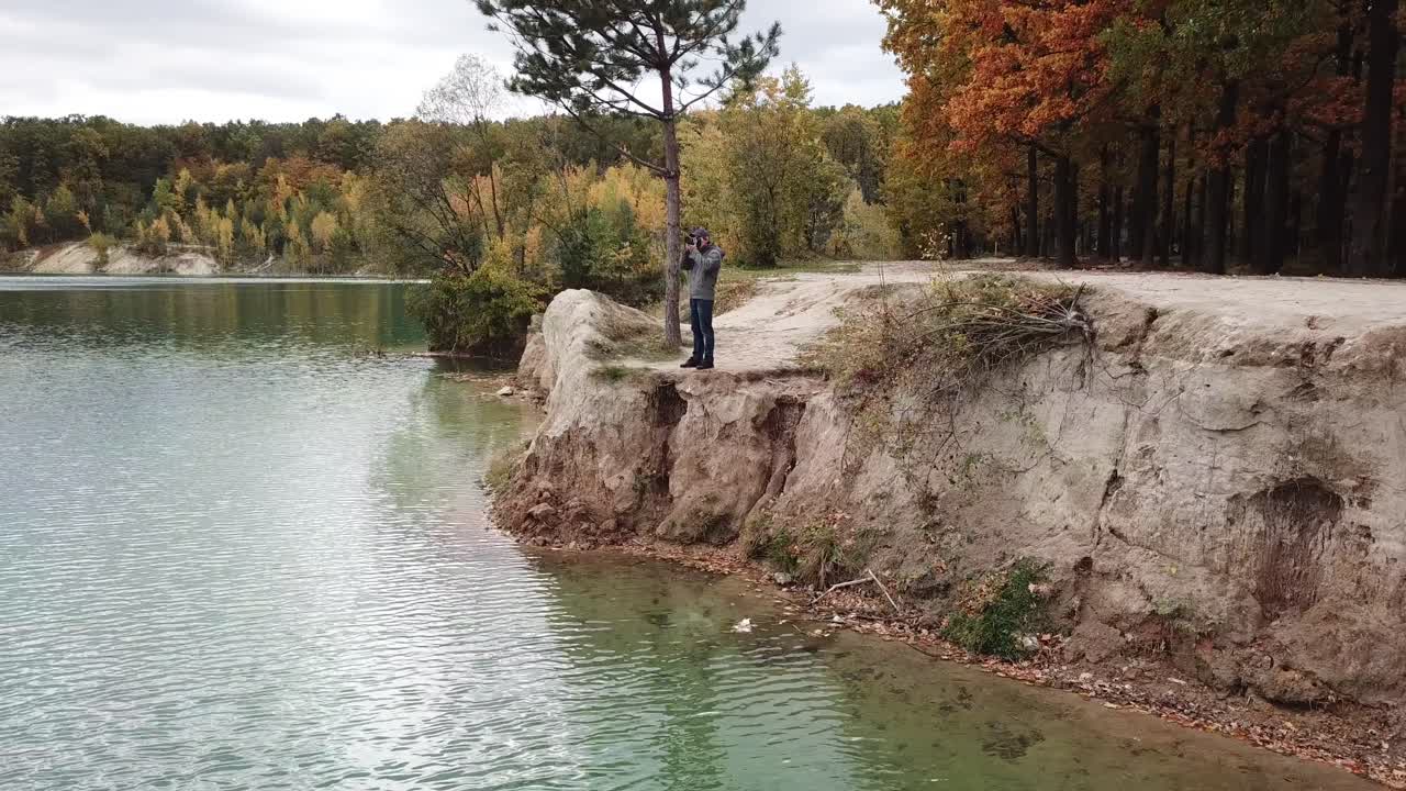 Man taking photo of landscape. Aerial view of man photographer taking photo on lake shore