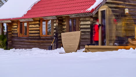 Time-lapse-shot-of-people-build-Barrel-Sauna-in-snow-beside-wooden-apartment-house-during-winter-vacation