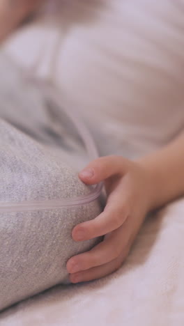 little child undergoes procedure with inhaler lying in soft bed with grey blanket in room close focus on hand