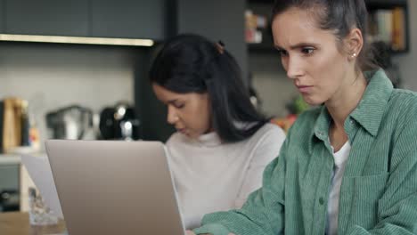 two very focused women working on computer at home