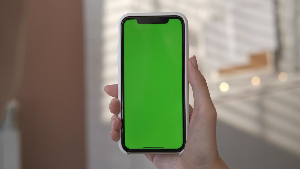 chica usando un teléfono inteligente con pantalla verde en la sala de estar