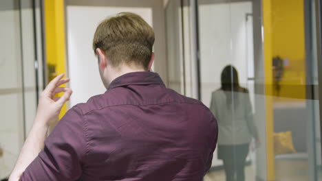 Rear-View-Businessman-Talking-On-Smartphone-In-Corridor