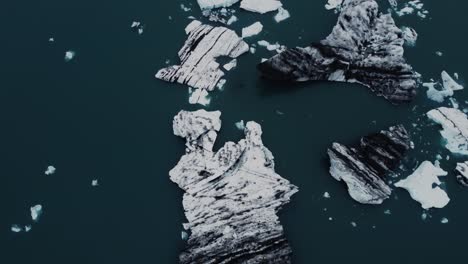 drone shot of beatiful black and white icebergs floating in a lagoon in iceland