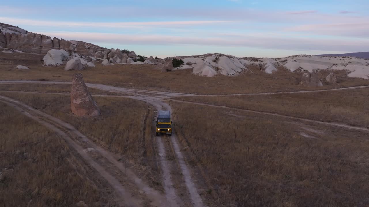 Fuoristrada 4x4 che attraversano una singolare valle rocciosa immersa nei colori del tramonto
