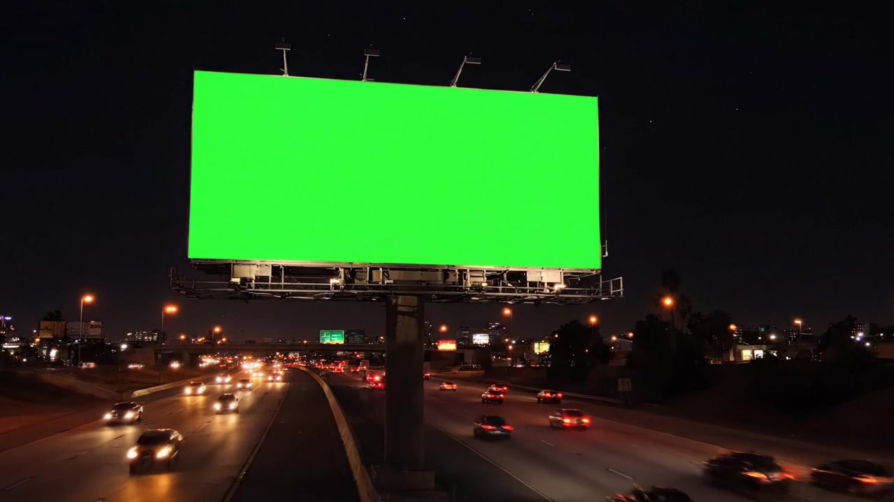 Et dynamisk perspektiv af et greenscreen-billboard i skumringen og om natten, der viser trafikstrøm og byliv langs motorvejen.