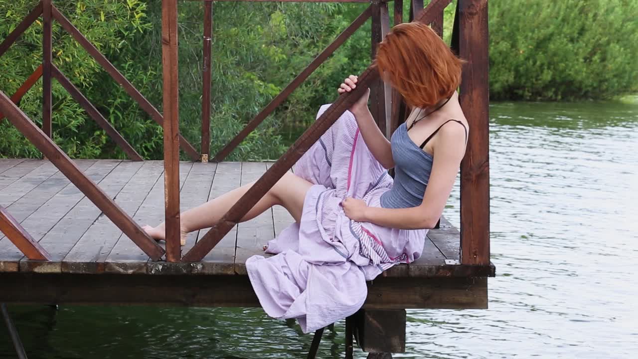 Young Woman Relaxing on a Wooden Dock by a Lake