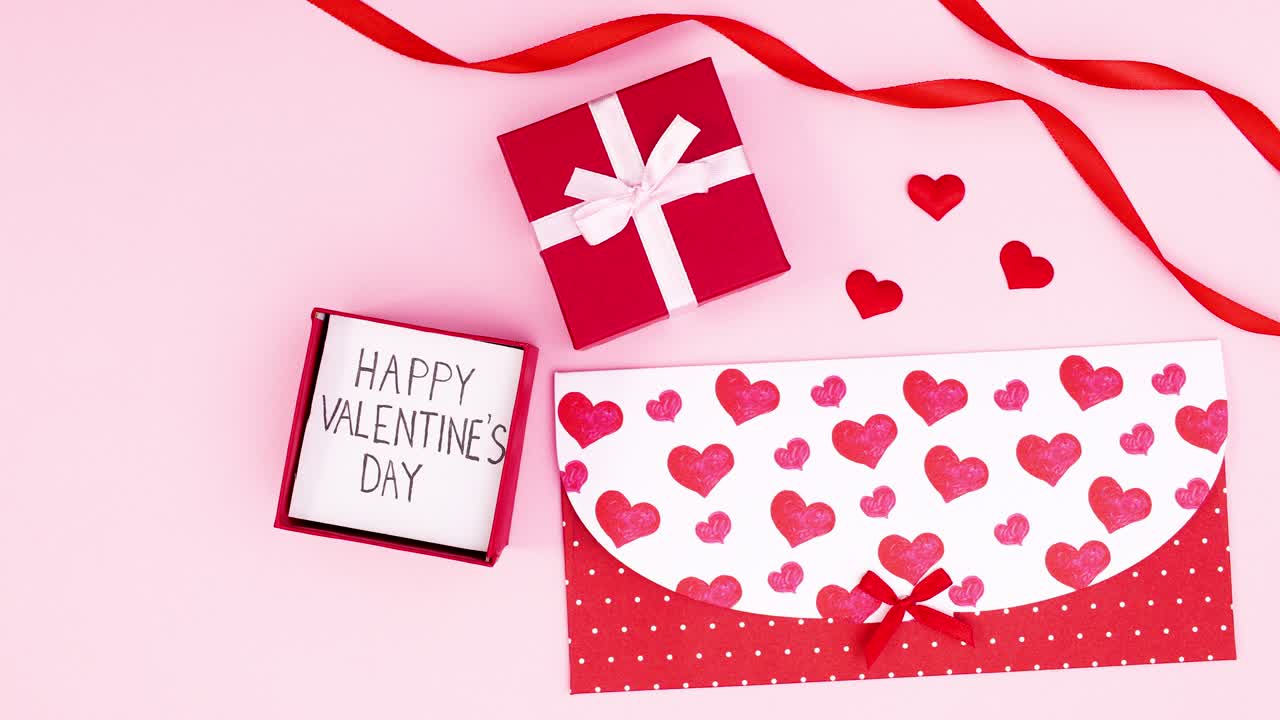 Happy valentine's day text in gift on pink theme with ribbons and envelope. Stop motion