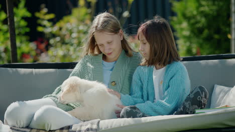 two girls playing with a puppy, sitting on a swing in the backyard of the house