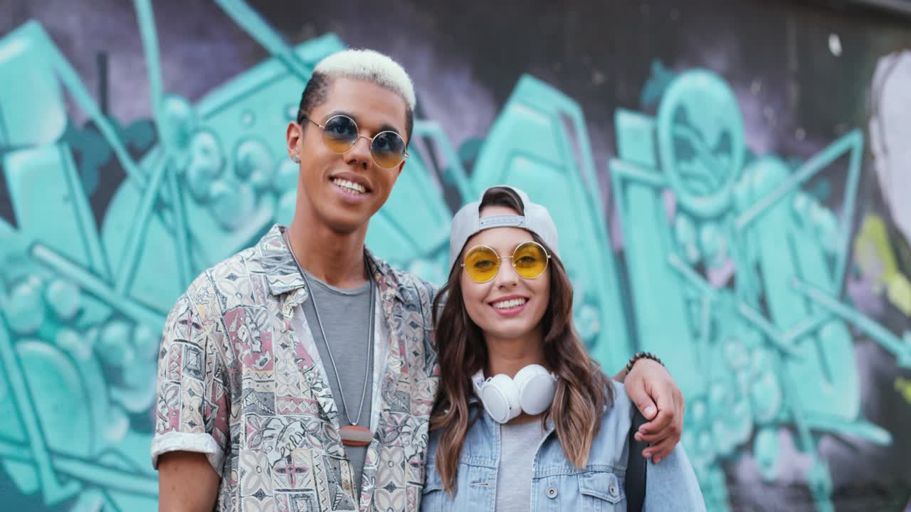 포옹과 카메라에 미소 사랑에 세련 된 옷에 hipster 커플