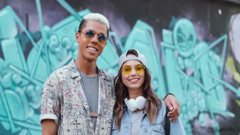 pareja hipster con ropa elegante enamorada abrazándose y sonriendo a la cámara