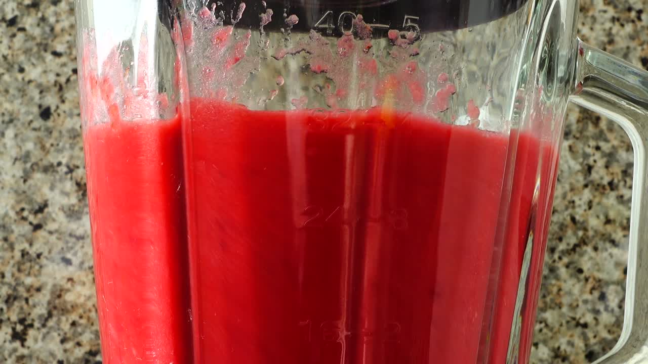 Preparazione nel frullatore di un cocktail con lamponi, banane e mele.